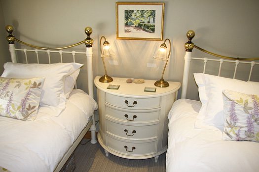 Twin bedroom at The Bothy with matching wrought-iron beds and antique bedside dresser