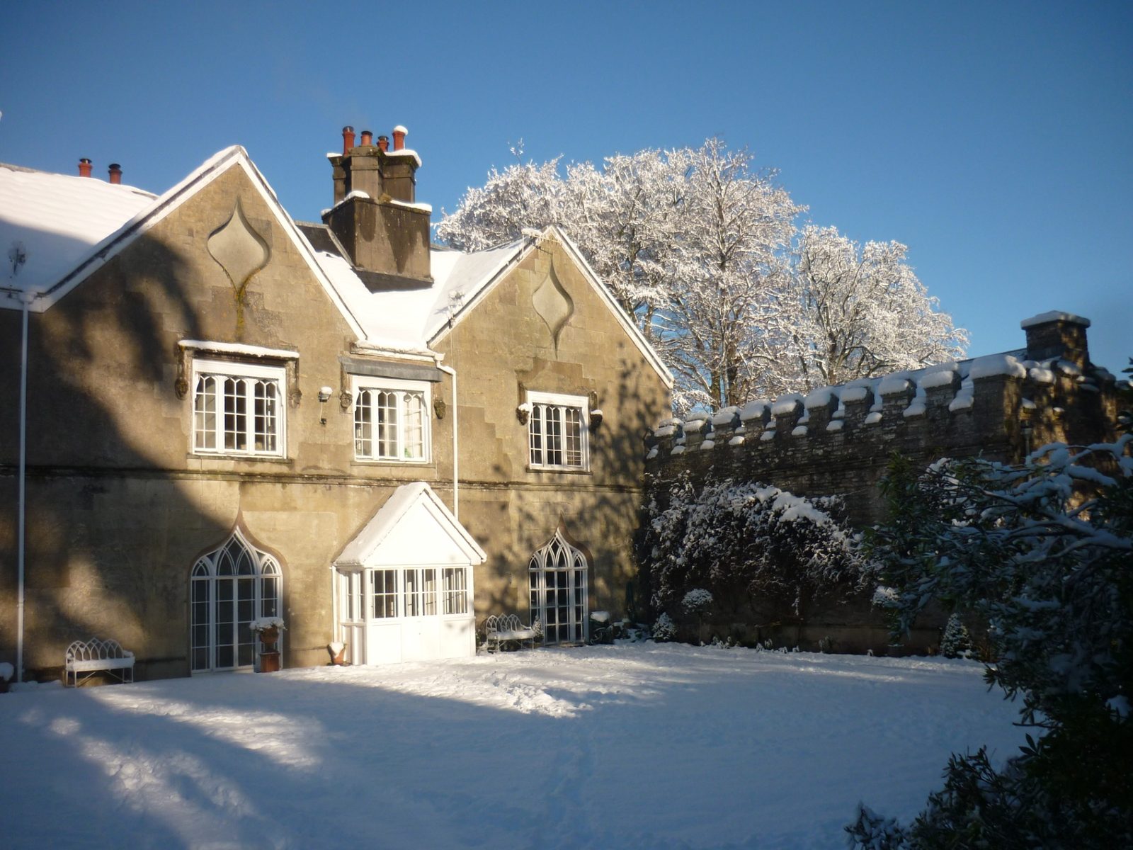The Georgian gothic facade of Ty Mawr House under fresh snow with a clear blue sky overhead
