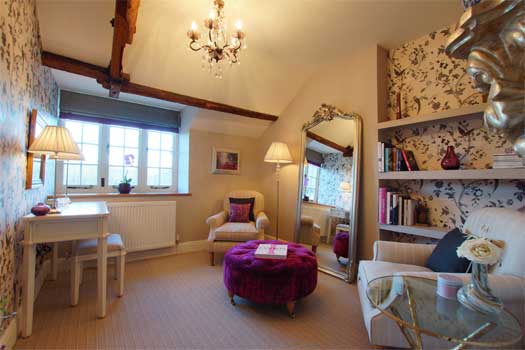 Elegant dressing area at The Cottage with velvet ottoman, floor mirror, writing desk and floral wallpaper