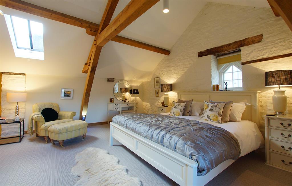 Vaulted master bedroom at The Laundry with exposed timber trusses, skylight and country furnishings