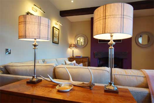 Detail of the sitting room at The Cottage with matching table lamps, tartan shades and antler centrepiece