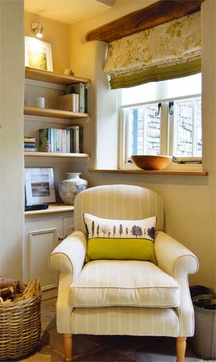 Cosy reading nook at The Bothy with striped armchair, built-in bookshelves and window seat