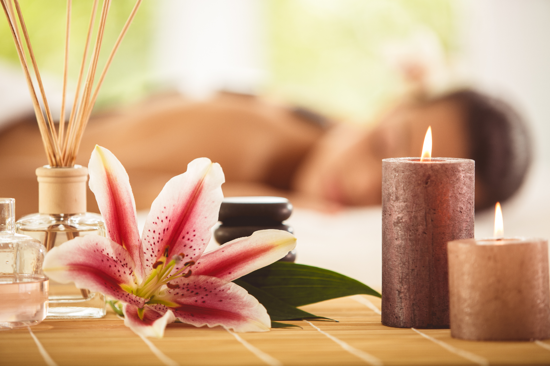 Spa treatment setting with lily, candles, hot stones and reed diffuser