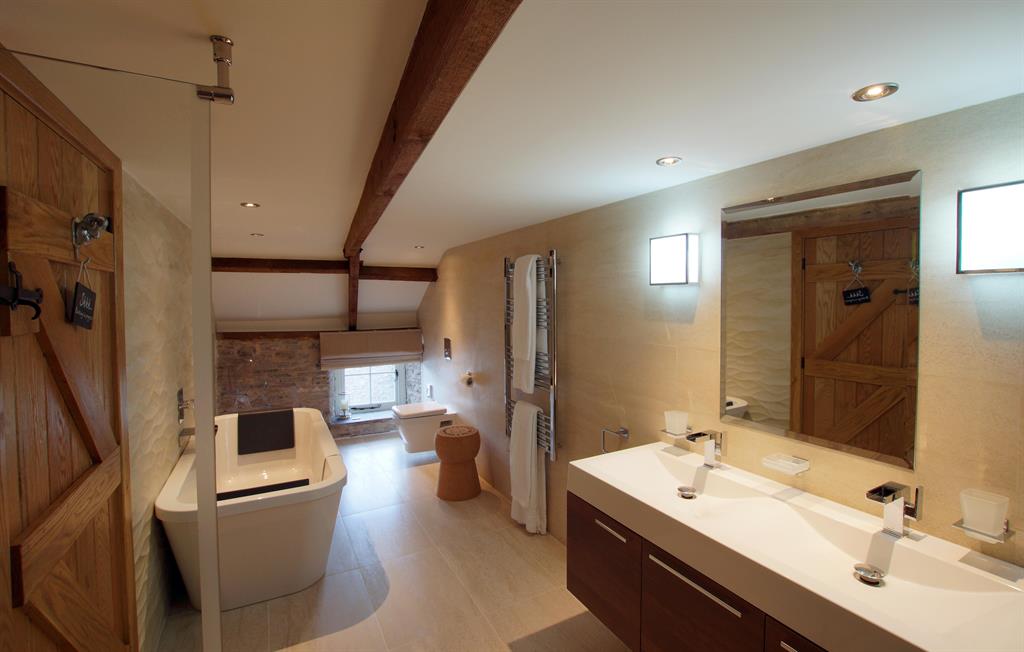 Spacious bathroom at The Coach with freestanding bath, twin basin vanity and exposed beams beneath the vaulted ceiling